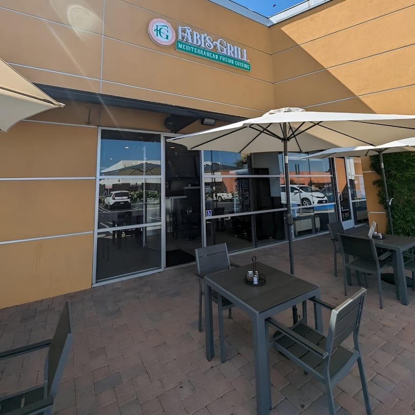 Fabi's Grill Mediterranean Fusion Cuisine storefront with outdoor patio seating and umbrellas on a sunny day.