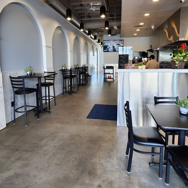Interior of Fabi's Grill with arched walls, black tables and chairs, and a counter with a chef.