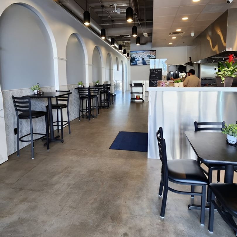 Interior of Fabi's Grill with arched walls, black tables and chairs, and a counter with a chef.