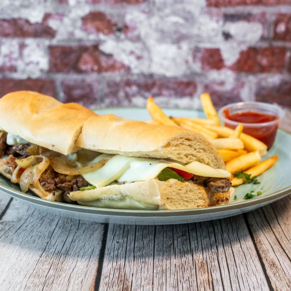 Fabi's Grill cheesesteak sandwich with steak, onions, peppers, cheese, and fries with ketchup.